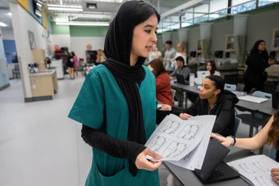 Fatema Adel, a Rio Americano student in the medical assistant pathway program, passes out papers on Monday before U.S. Department of Health and Human Services Secretary Xavier Becerra speaks with students from Rio Americano High School during a visit to the Sacramento region to highlight his department’s efforts to expand the health care workforce.