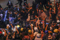 Pro-democracy activists remove barbed wire barricades during their march to the Government House, prime minister's office during a protest march in Bangkok, Thailand, Wednesday, Oct. 21, 2020. Thailand's prime minister on Wednesday pleaded with his countrymen to resolve their political differences through Parliament, as student-led protests seeking to bring his government down continued for an eighth straight day. (AP Photo/Sakchai Lalit)