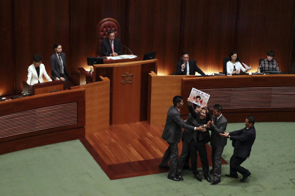 A pro-democracy lawmaker is forcibly removed from the chamber of the Legislative Council as Hong Kong Chief Executive Carrie Lam, left, speaks at a question and answer session with lawmakers in Hong Kong, Thursday, Oct. 17, 2019. (AP Photo/Mark Schiefelbein)