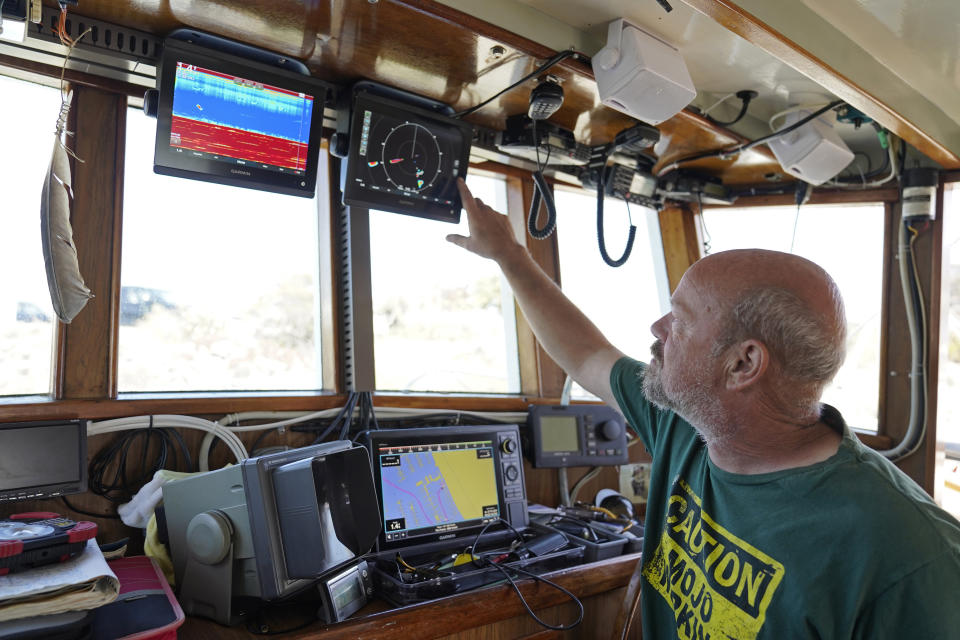 Salmon fisherman Mike Hudson looks over instruments in the cabin of his boat at the Berkeley, Calif., Marina on Thursday, July 22, 2021. Baby salmon are dying by the thousands in one river and an entire run of endangered salmon could be wiped out in another. The plummeting catch has led to skyrocketing retail prices for salmon, hurting customers who say they can no longer afford the $35 per pound of fish, said Hudson, who has spent the last 25 years catching and selling salmon at farmers' markets in Berkeley. (AP Photo/Eric Risberg)