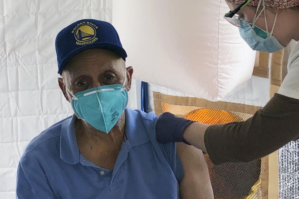 Martin Auzenne, 73, left, receives a COVID-19 vaccine shot from a health care worker at a vaccination site in the Bayview neighborhood of San Francisco, Monday, Feb. 8, 2021. Counties in California and other places in the U.S. are trying to ensure they vaccinate people in largely Black, Latino and working-class communities that have borne the brunt of the coronavirus pandemic. San Francisco is reserving some vaccines for seniors in the two ZIP codes hit hardest by the pandemic. (AP Photo/Haven Daley)