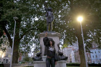 Jen Reid poses for photographs in front of the new black resin and steel statue portraying her entitled "A Surge of Power (Jen Reid) 2020" by artist Marc Quinn after the statue was put up this morning on the empty plinth of the toppled statue of 17th century slave trader Edward Colston, which was pulled down during a Black Lives Matter protest in Bristol, England, Wednesday, July 15, 2020. On June 7 anti-racism demonstrators pulled the 18-foot (5.5 meter) bronze likeness of Colston down, dragged it to the nearby harbor and dumped it in the River Avon — sparking both delight and dismay in Britain and beyond. (AP Photo/Matt Dunham)