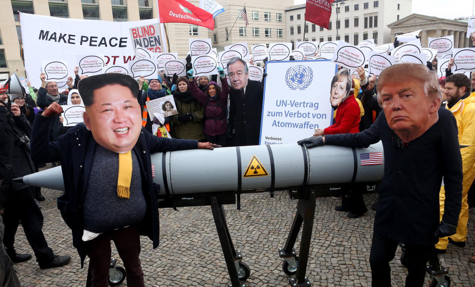 An activist with a mask of Kim Jong-un and another with a mask of U.S. President Donald Trump, march with a model of a nuclear rocket during a demonstration against nuclear weapons/Getty Images