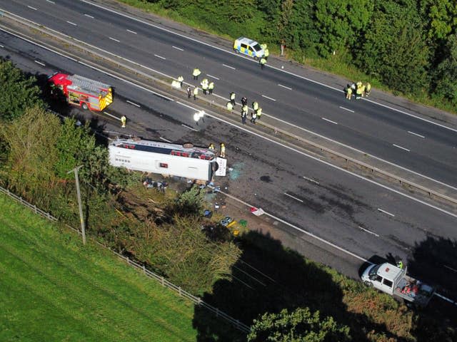 A coach on its side on a motorway hard shoulder