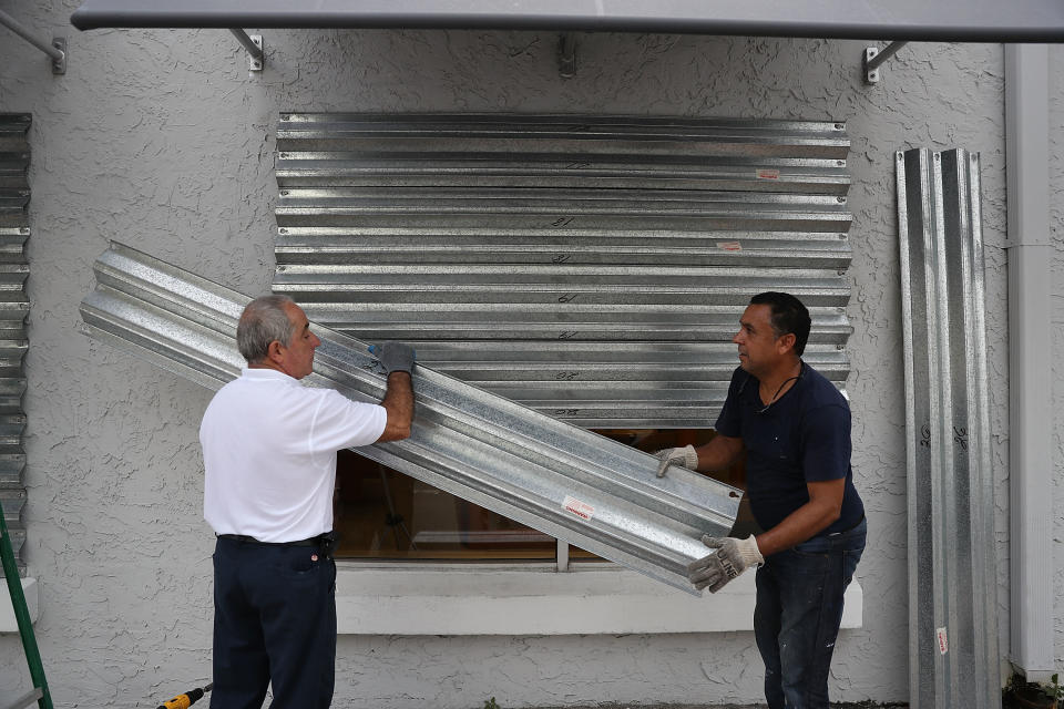 Gus Sousa and Winston Mora (L-R) put hurricane shutters on a business as they prepare for Hurricane Irma on September 6, 2017 in Miami.