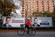 FILE PHOTO:A woman rides a bicycle alongside campaign posters of Rafal Trzaskowski and Patryk Jaki, the two main candidates running for Warsaw mayor in a local election on Sunday in Poland, in Warsaw, Poland October 18, 2018. REUTERS/Kacper Pempel/File Photo