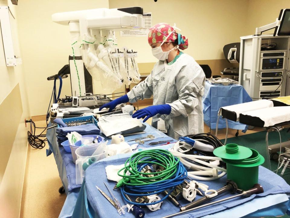 Surgical technician Mariah Hiner prepares for surgery with the Xi surgical robot in the background.