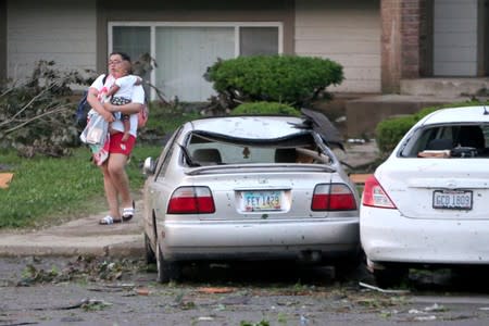 A woman leaves her apartment with a small child the morning after a tornado touched down overnight in Trotwood