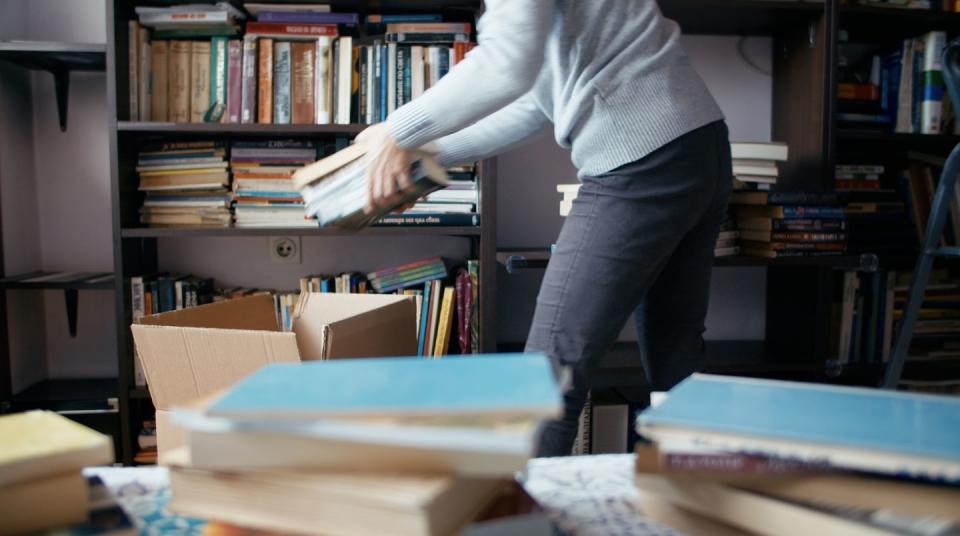 swedish death cleaning, woman packing boxes with books