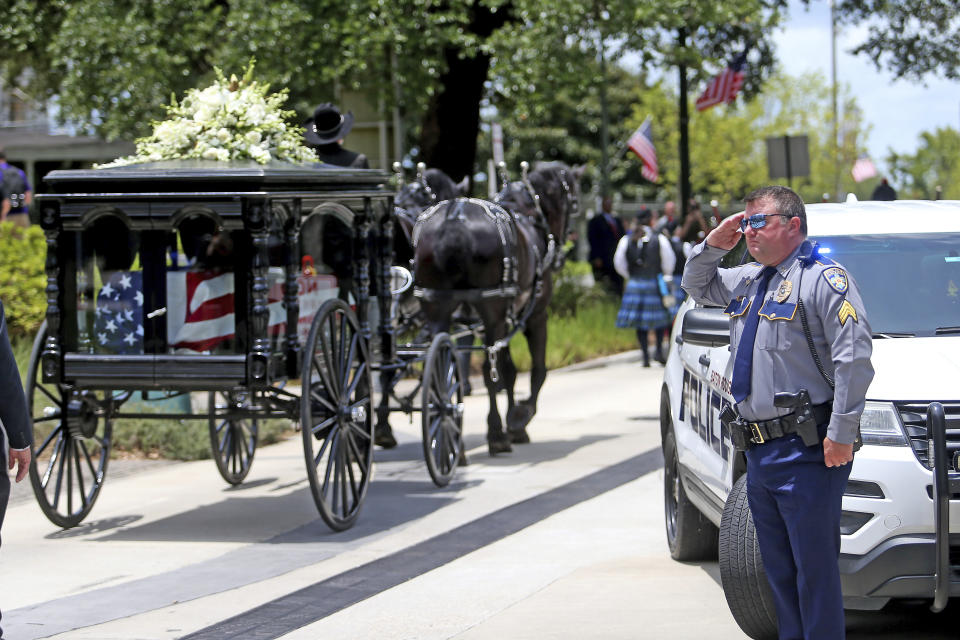 Members of law enforcement from all over the state line the route as a horse-drawn carriage carries former Louisiana Gov. Edwin Edwards away from the Louisiana State Capitol and down North Blvd. in Baton Rouge, La., Sunday, July 18, 2021. A processional featuring a law enforcement motorcade and the Southern University Marching Band was held though the streets of downtown Baton Rouge, ending at the Old State Capital building where a private funeral service was held. The colorful and controversial four-term governor died of a respiratory illness on Monday, July 12th at the age of 93. (AP Photo/Michael DeMocker)