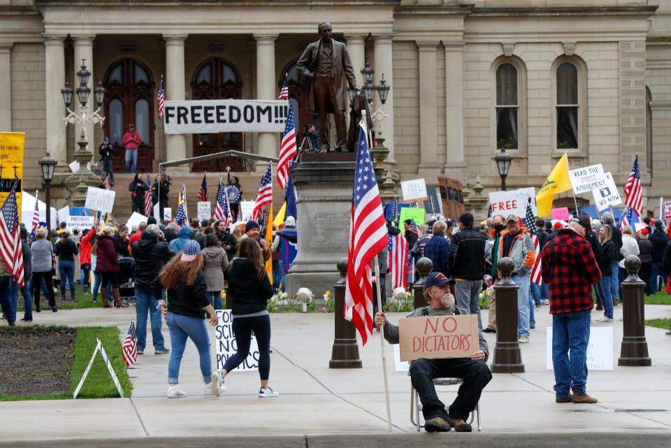 In this April 30, 2020, photo, protesters rally at the State Capitol in Lansing, Mich. Gun-carrying protesters have been a common sight at some demonstrations calling for coronavirus-related restrictions to be lifted. But an armed militia’s involvement in an angry protest in the Michigan statehouse Thursday marked an escalation that drew condemnation and shone a spotlight on the practice of bringing weapons to protest.  (AP Photo/Paul Sancya)