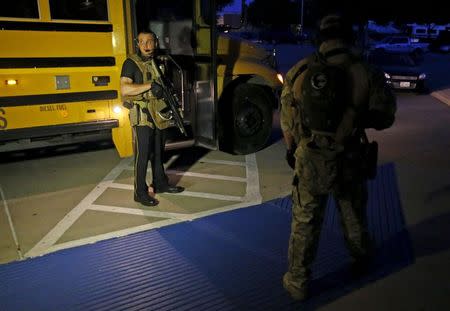 Police officers stand near a school bus used to evacuate attendees of the Muhammad Art Exhibit and Contest sponsored by the American Freedom Defense Initiative after a shooting outside the Curtis Culwell Center where the event was held in Garland, Texas May 3, 2015. REUTERS/Mike Stone