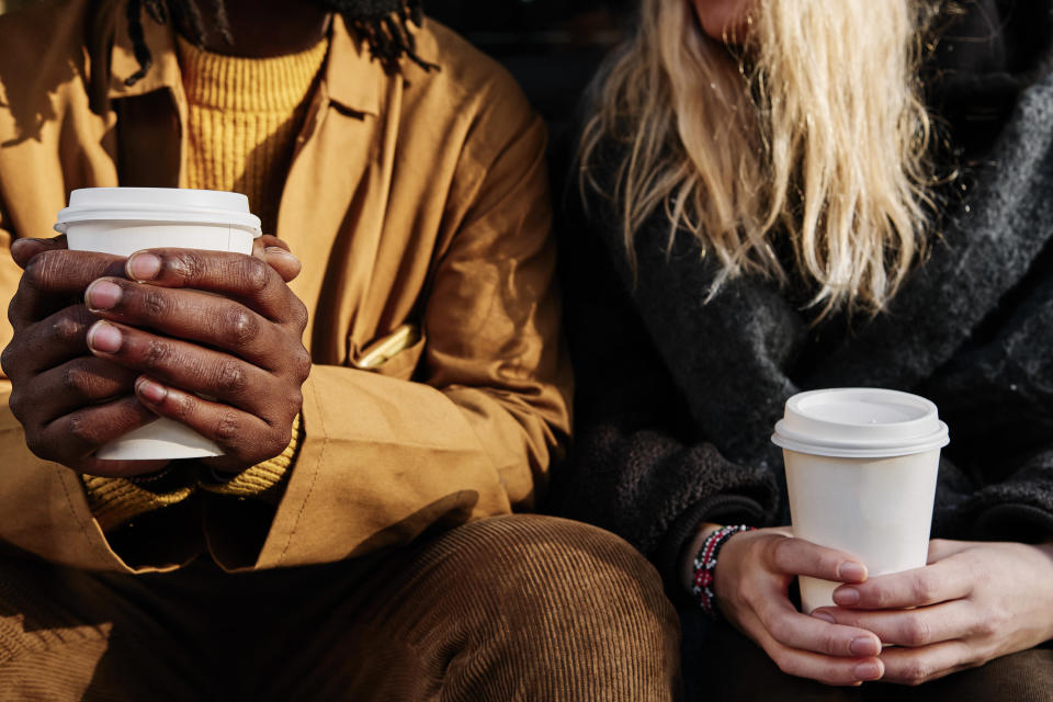 two people holding to-go coffee cups