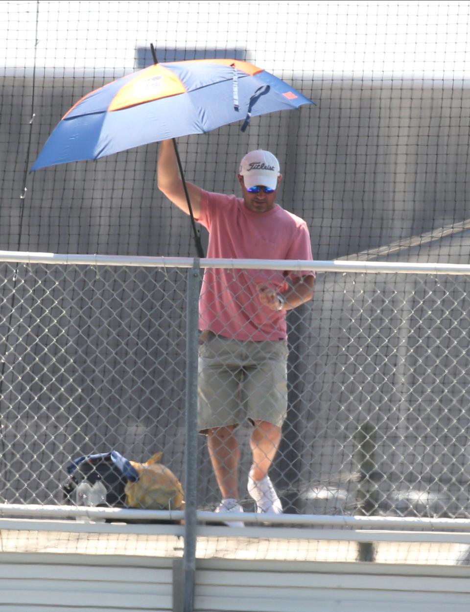 Robert Alfano of Demarest tries to use his Syracuse University umbrella to cool off while watching a baseball game in Wood-Ridge, NJ on May 21, 2022.