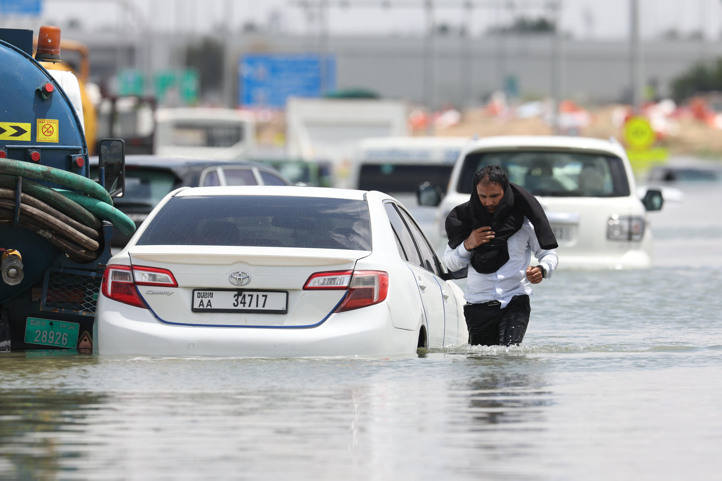 A driver walks through floodwaters after abandoning his vehicle following a rainstorm.