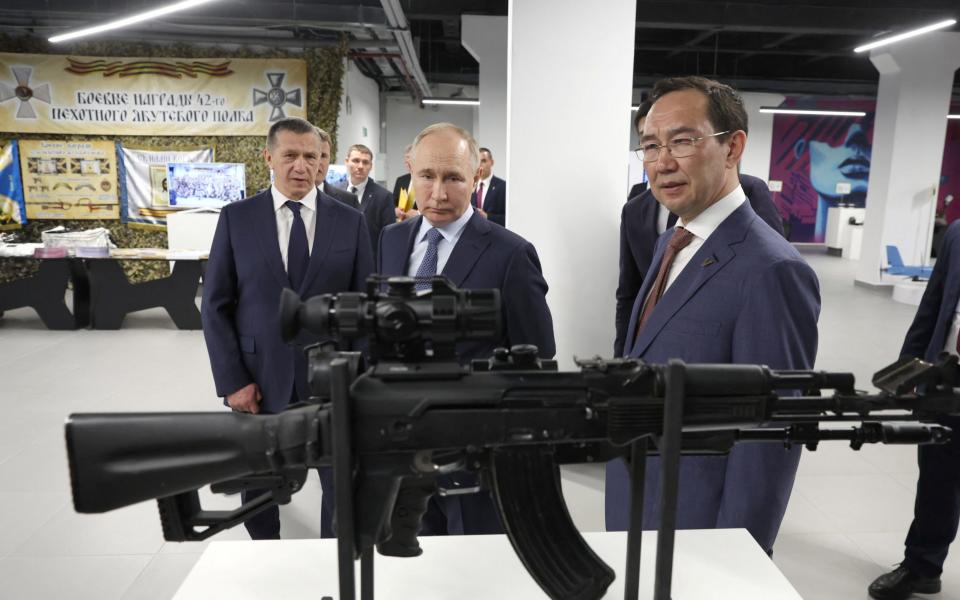 Vladimir Putin is accompanied by a regional leader as he inspects models of weapons and equipment produced in the far eastern regions.