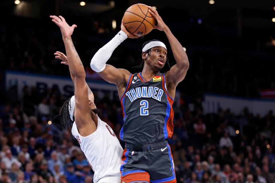 Oklahoma City Thunder guard Shai Gilgeous-Alexander, right, looks to pass the ball away from Cleveland Cavaliers forward Lamar Stevens during the first second of an NBA basketball game Friday, Jan. 27, 2023, in Oklahoma City. (AP Photo/Nate Billings)