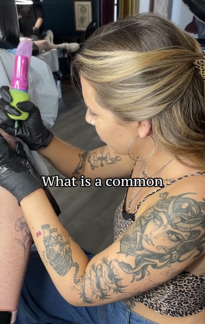 Tattoo artist working on client's arm, both have multiple tattoos. Text: 