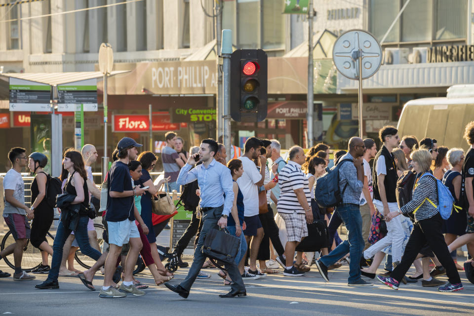 People walking across a busy street in Melbourne.