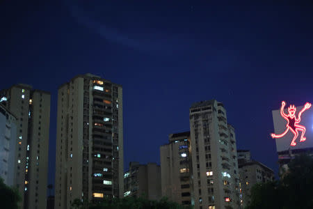 A sign for a popular ham brand is illuminated next to buildings at nightfall in Caracas, Venezuela, April 2, 2019. A woman who lives in the building below the sign said, "I don't like to have a devil on my head." REUTERS/Ivan Alvarado