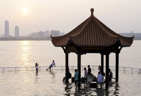 Tourists take pictures near a pavilion flooded by the swollen Yangtze River in Wuhan, Hubei province, June 19, 2015. Picture taken June 19, 2015. REUTERS/China Daily