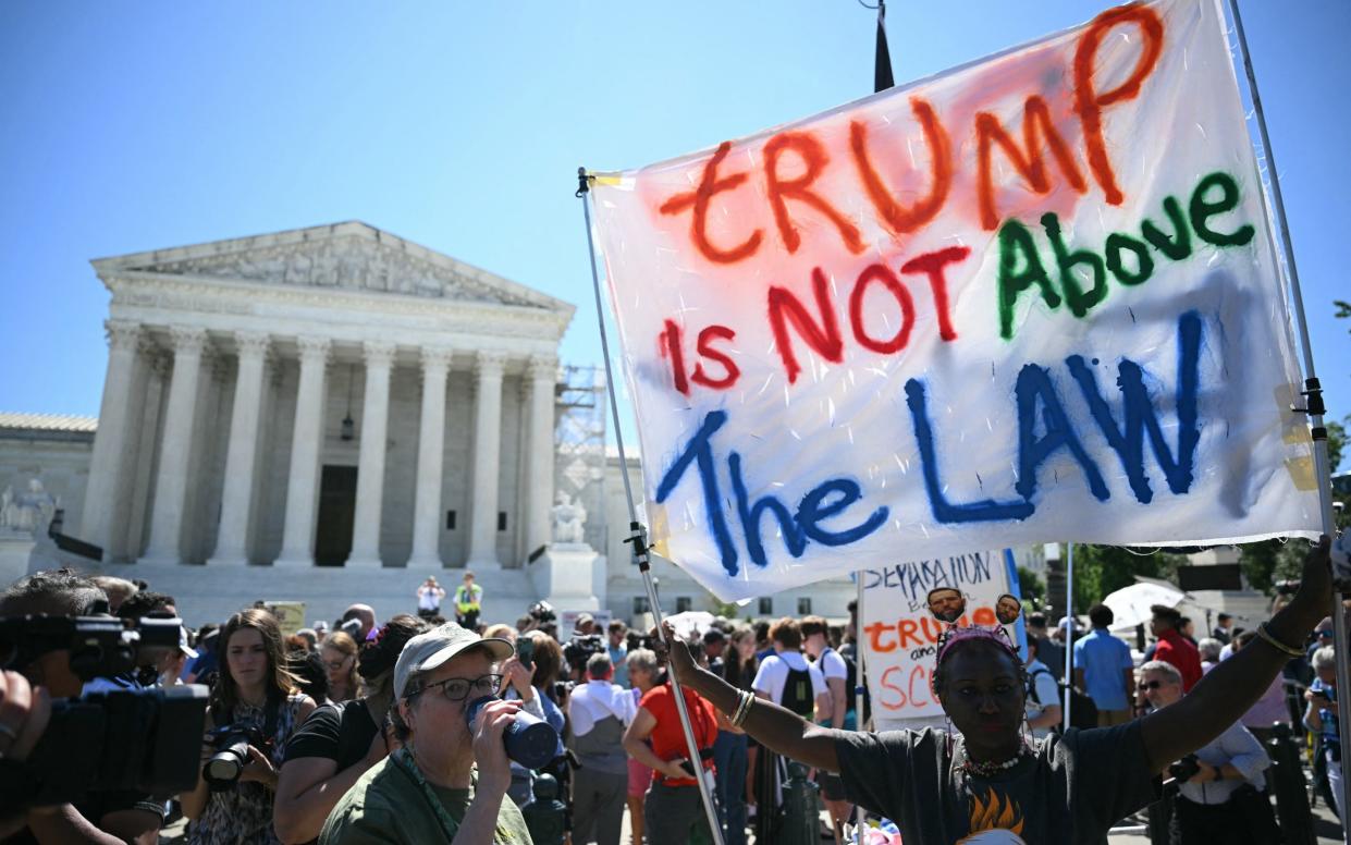 People hold anti-Trump signs in front of the US Supreme Court