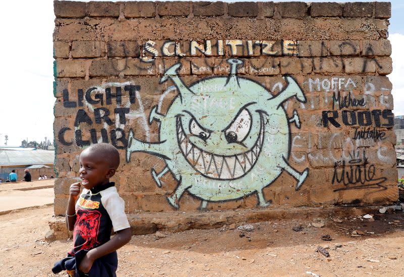 FILE PHOTO: A boy stands in front of a graffiti promoting the fight against the coronavirus disease (COVID-19) in the Mathare slums of Nairobi