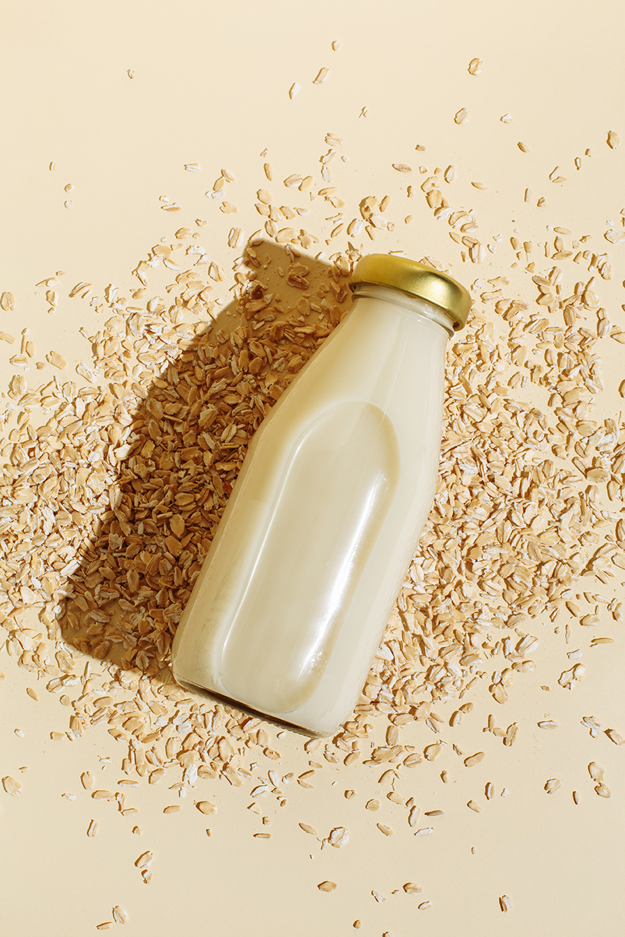 a bottle of oatmilk on top of scattered oats