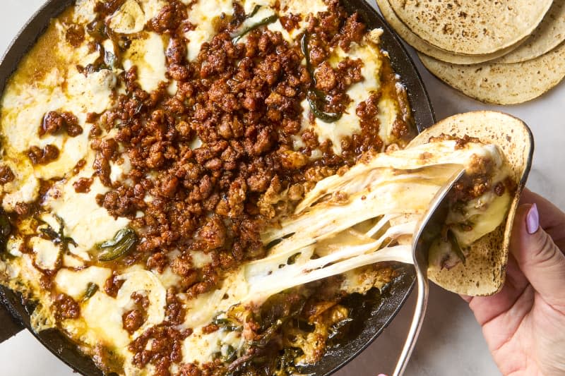 overhead shot of a scoop of queso fundido being put into a small tortilla