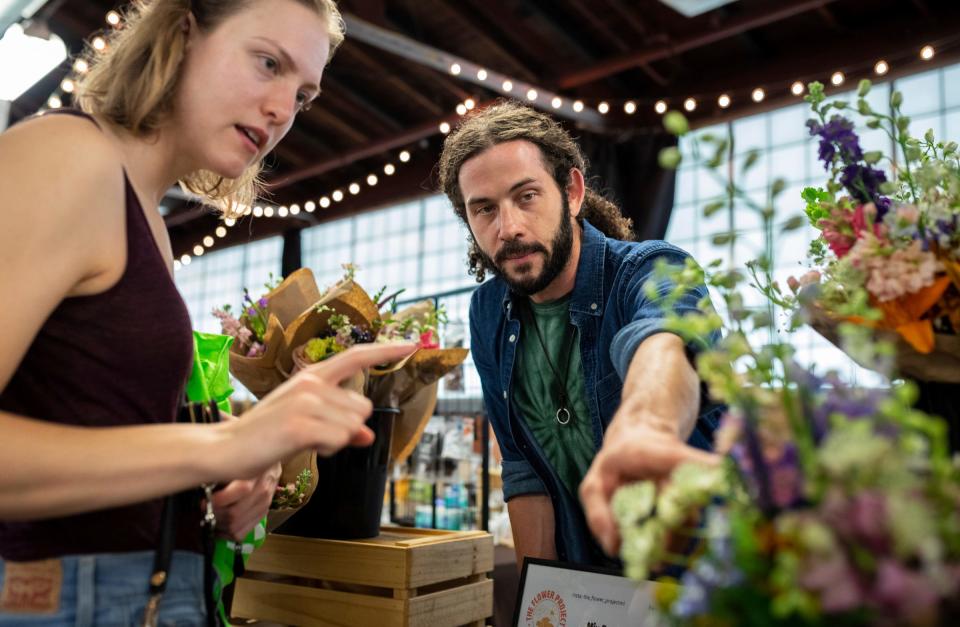 Jennifer MacDonald, left, shops for flowers at a flower booth run by Brent Grant, co-owner of The Flower Project, during the Royal Oak Farmers Market in Royal Oak on Saturday, June 29, 2024. The Flower Project is a small flower farm in Ferndale dedicated to growing unique, specialty flowers.