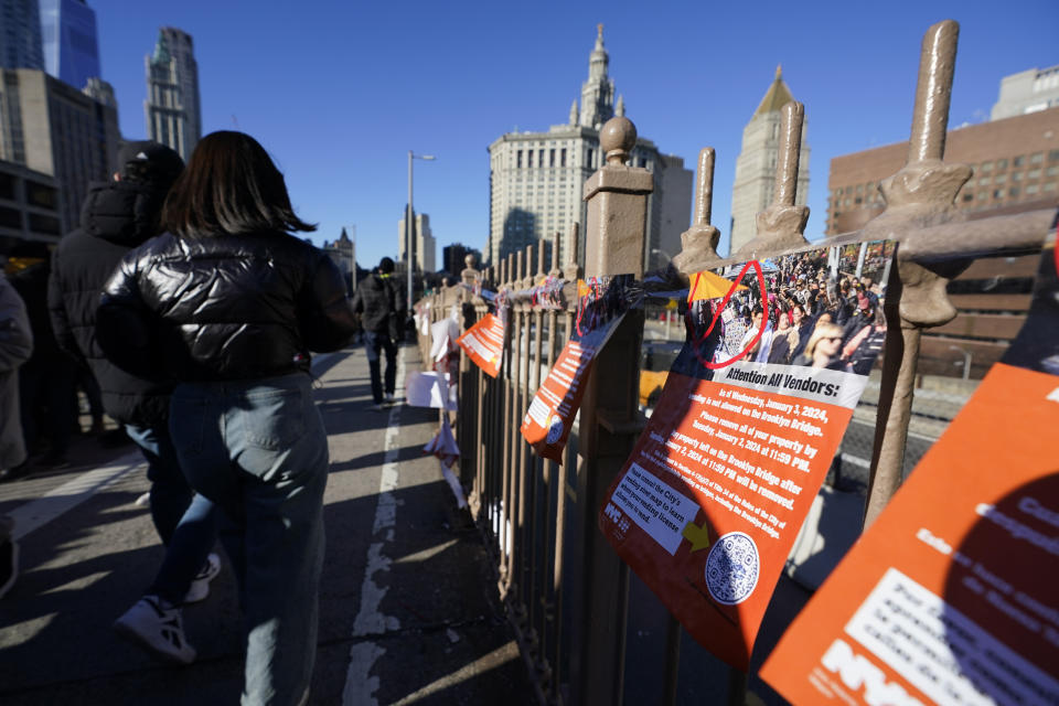 Notices are taped up on the pedestrian walkway of the Brooklyn Bridge in New York, Tuesday, Jan. 2, 2024. The notices warn vendors that no more vending will be allowed on the bridge starting January 3, 2024. (AP Photo/Seth Wenig)