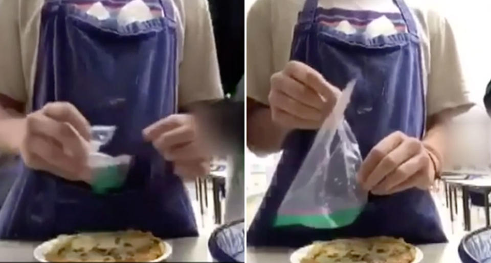 A teenage boy in an apron holds a clear plastic bag filled with liquid while he prepares a crepe.