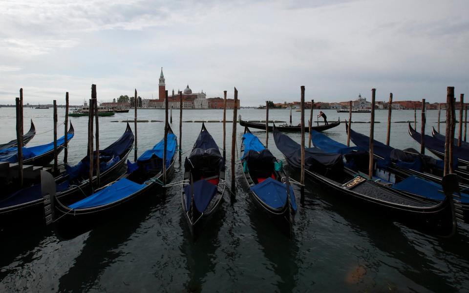 Gondolas moored at the Canal grande (Grand Canal) in Venice, Italy. The coronavirus pandemic has ground Italy's most-visited city to a halt and devastated its economy -  Antonio Calanni/AP
