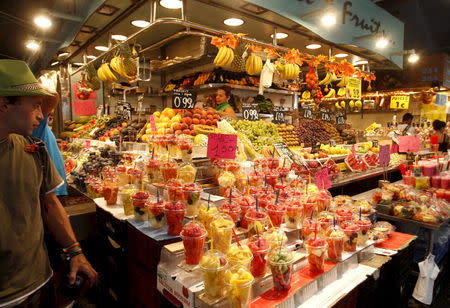 Tourists look at a fruit juice stand in the La Boqueria market in Barcelona, Spain, in this August 31, 2012 file photo. REUTERS/Gustau Nacarino/Files