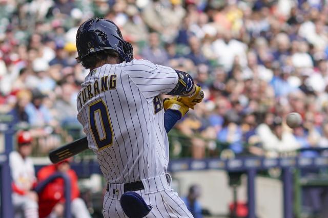 Milwaukee Brewers' Willy Adames, left, places a cheesehead on