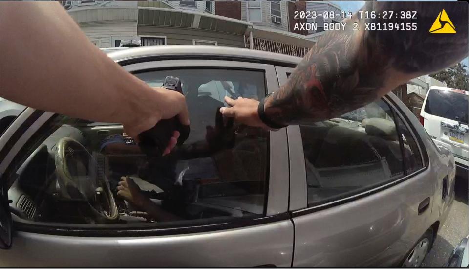 officer's arm visible pointing gun at car window