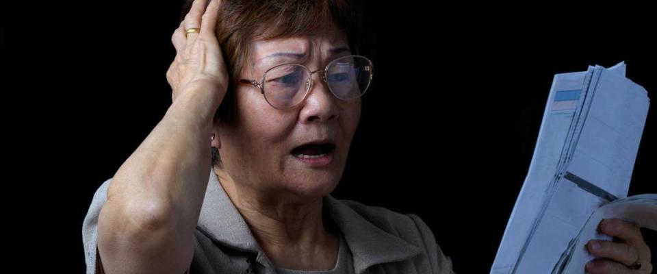 senior woman stressed out looking at bills