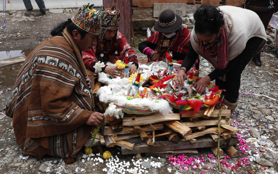 Guías espirituales preparan una ofrenda durante la celebración del "Martes de Challa", en la cual la gente compra comida, lanza dulces, quema incienso y decora sus casas, negocios y autos para agradecer a la Pachamama o Madre Tierra, en La Paz, Bolivia, el martes 16 de febrero de 2021. (AP Foto/Juan Karita)