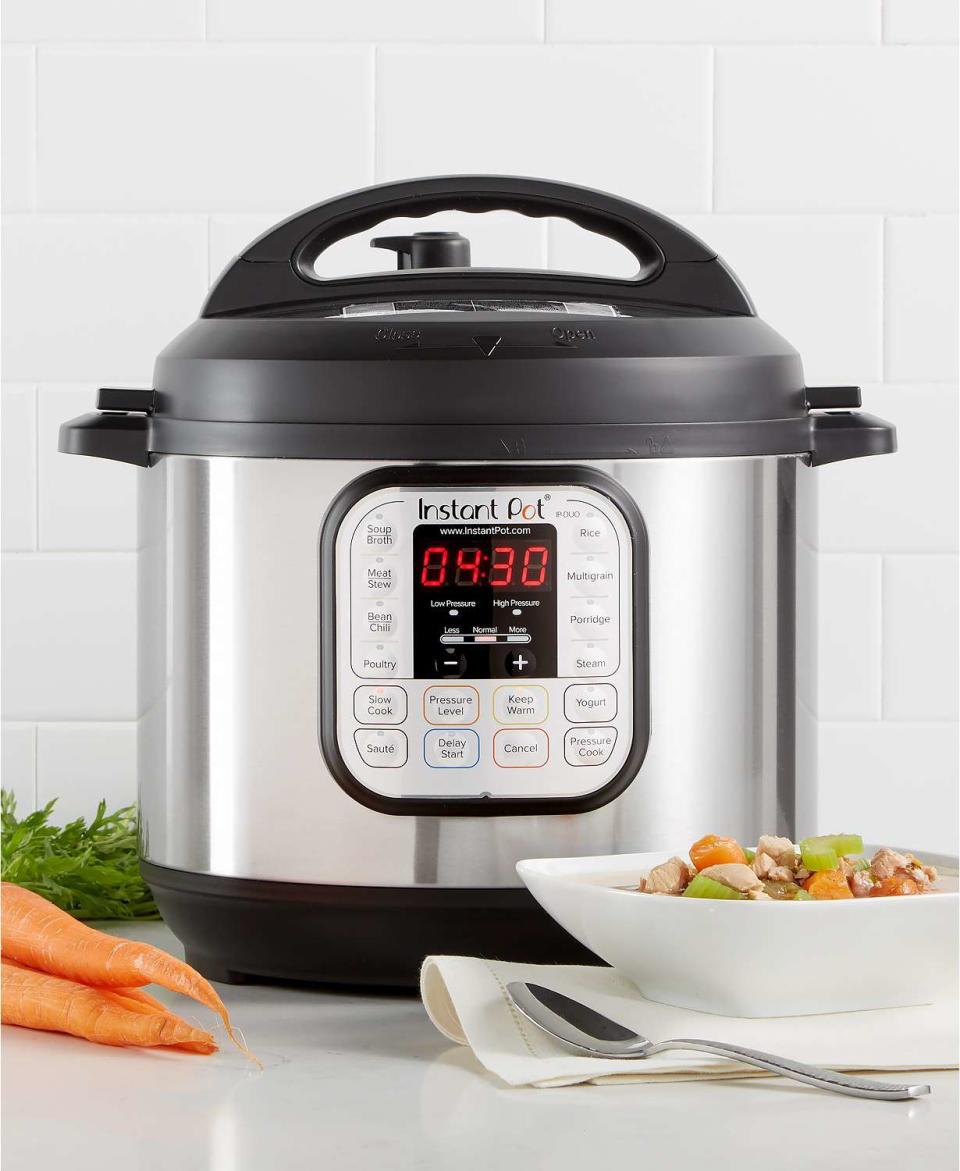 Black and silver instant pot on a white counter with carrots and a bowl of veggies next to it