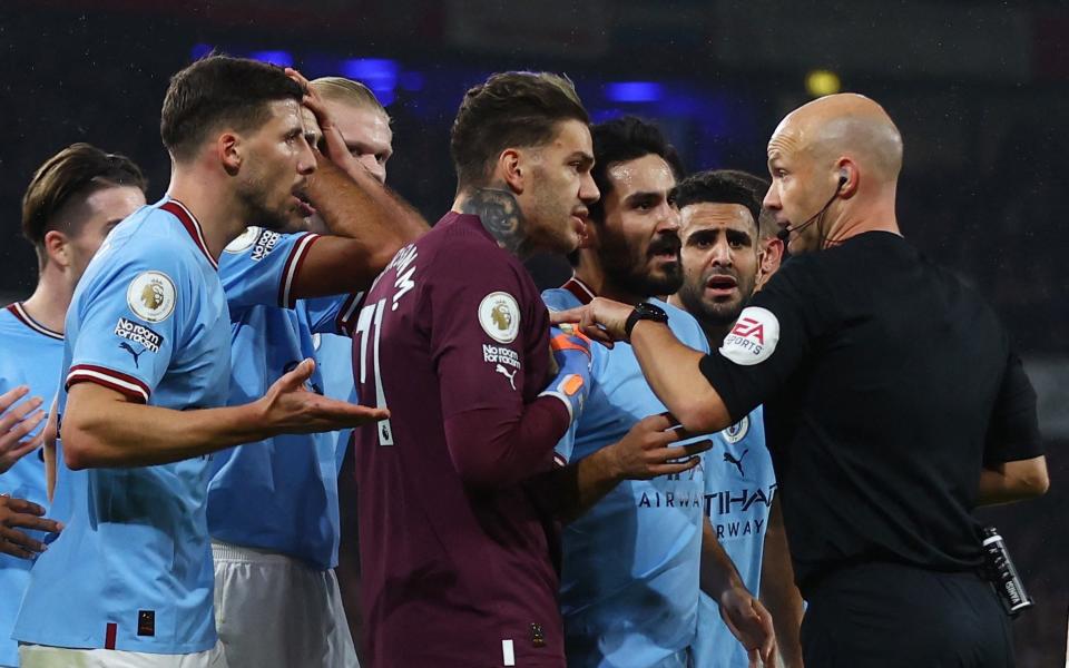 Referee Anthony Taylor is surrounded by Manchester City players/New Premier League rules 23/24: Dissent, time-wasting and tackle leniency