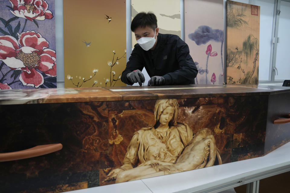 A worker fixes screws on a paper coffin at the factory of LifeArt in Hong Kong, Friday, March 18, 2022. Hong Kong is running short of coffins during its deadliest outbreak of the coronavirus pandemic. LifeArt, a company in Hong Kong is trying to make an alternative, cardboard coffin, which it says is environmentally-friendly. (AP Photo/Kin Cheung)