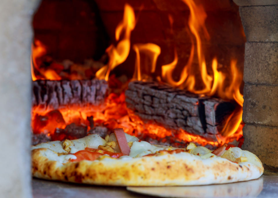 Pizza being pulled out of pizza oven.