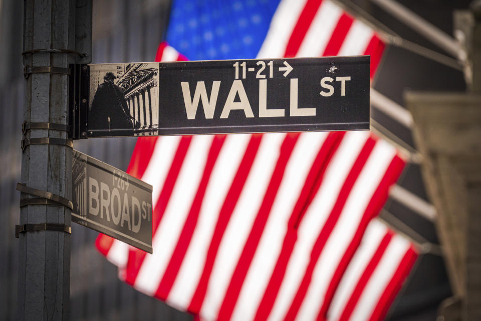 The sun shines through the U.S. flags flying in front of the New York Stock Exchange at the corner of Wall and Broad Streets in New York City, Tuesday, Nov. 14, 2023. (AP Photo/J. David Ake)