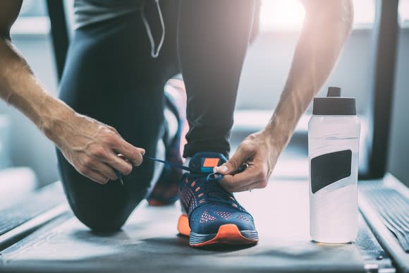 A man kneeling tying his shoelaces