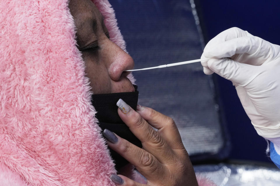 A healthcare worker takes a nasal swab sample from a woman to test for COVID in Quito, Ecuador, Tuesday, Jan. 11, 2022. The provincial government testing center is offering low-cost COVID PCR tests as an upsurge in infections is feared following the holiday season. (AP Photo/Dolores Ochoa)