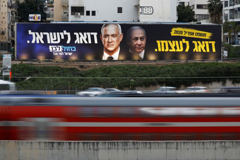 Traffic moves past a Blue and White party election campaign poster, depicting party leader Benny Gantz, and Israeli Prime Minister Benjamin Netanyahu, in Tel Aviv