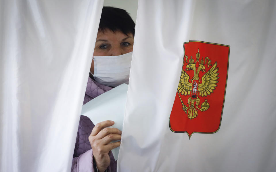 A woman wearing a face mask to protect against coronavirus infection leaves a voting booth at a poling station during Leningrad region's governor and municipal elections in Luppolovo village, outside St. Petersburg, Russia, Sunday, Sept. 13, 2020. Leningrad region is the territory surrounding St. Petersburg. Elections are being held to choose governors and legislators in about half of Russia's regions. (AP Photo/Dmitri Lovetsky)