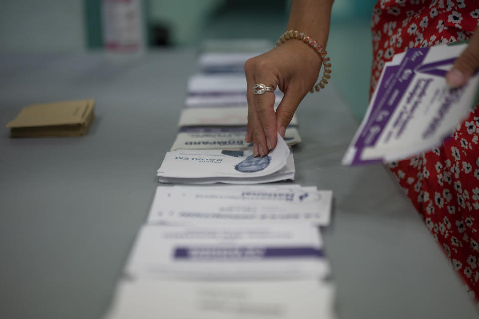 A woman selects ballots in the first round of the French parliamentary election, Sunday, June 12, 2022 in Marseille, southern France. Voters are choosing lawmakers as President Emmanuel Macron seeks to secure his majority while under growing threat from a leftist coalition. (AP Photo/Daniel Cole)