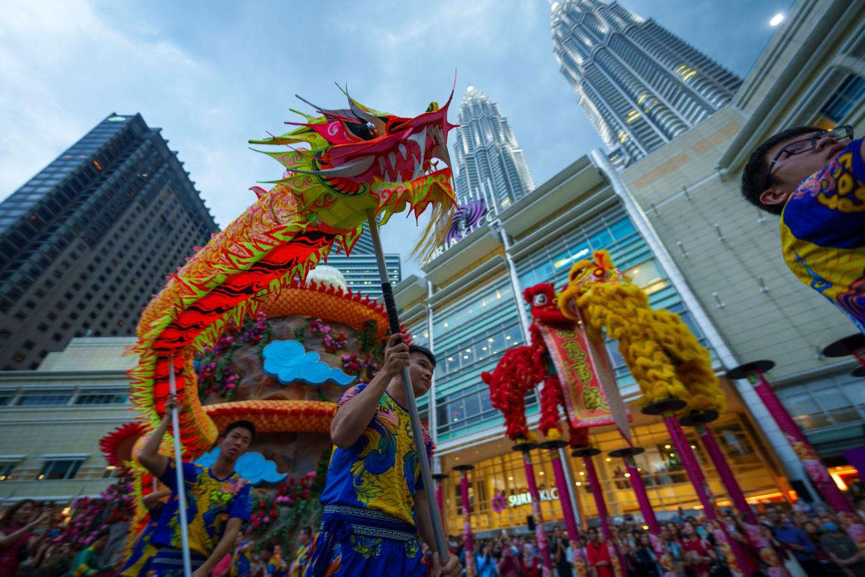 Lion and Dragon dance troupe performs next to lunar new year decorations with the background of Petronas Twin Towers in Kuala Lumpur, Malaysia, Thursday, Jan. 18, 2024. The Chinese Lunar New Year began on Feb. 10, marking the start of the Year of the Dragon, according to the Chinese zodiac. (AP Photo/Vincent Thian)