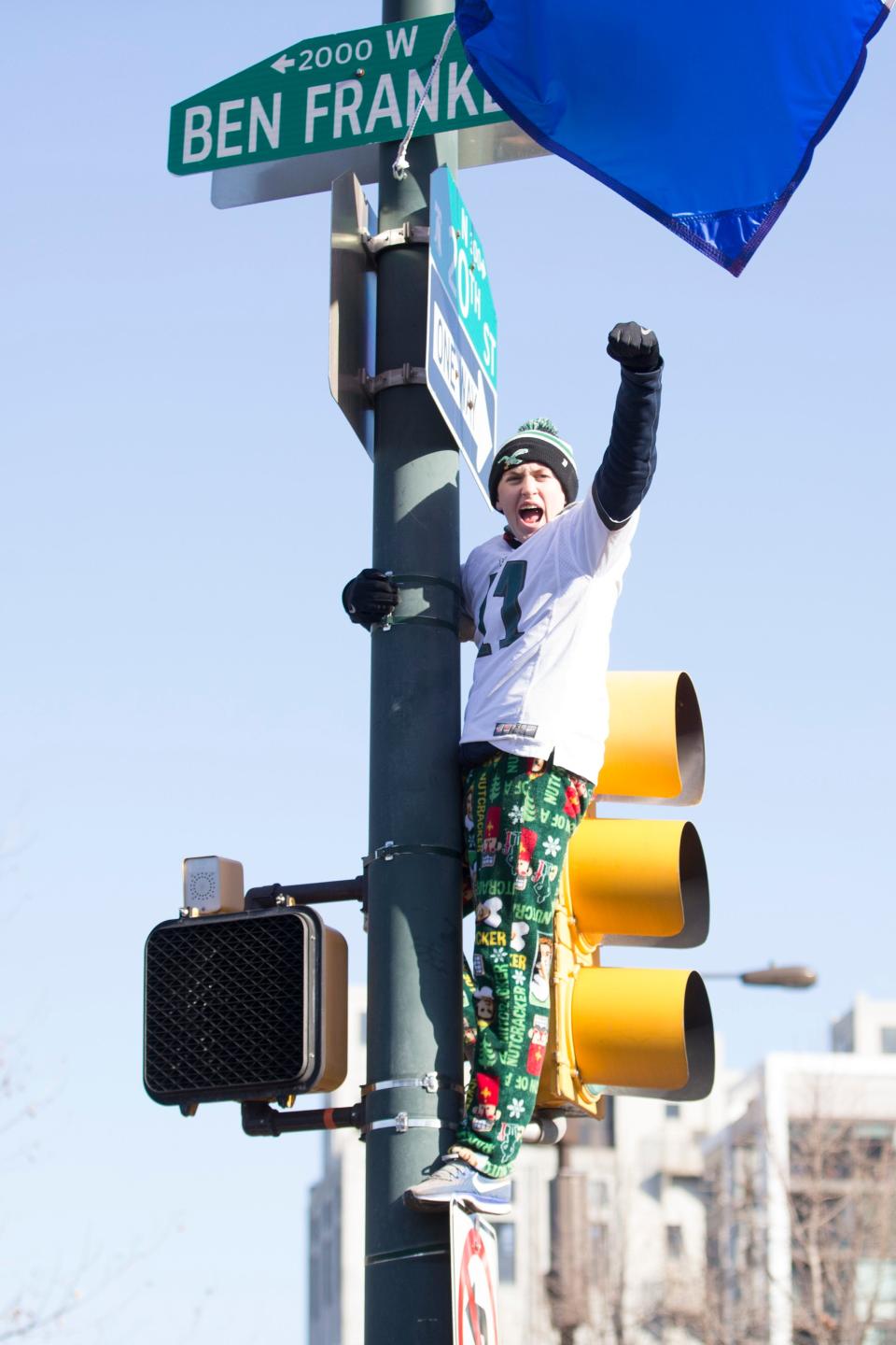 A fan climbs a light pole during the Super Bowl LII parade on February 8, 2018 in Philadelphia, Pennsylvania.